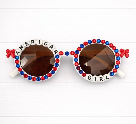 White round kids sunglasses with red and blue rhinestones and "AMERICAN GIRL" lettering around the frames