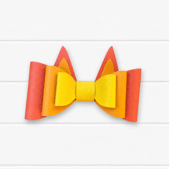 Faux leather kids hair bow with orange outer layer, light orange middle layer, and yellow center with two pointy heeler ears coming out of top that make it look like Bingo from Bluey.
