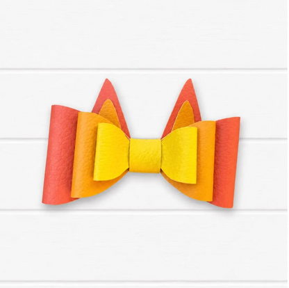 Faux leather kids hair bow with orange outer layer, light orange middle layer, and yellow center with two pointy heeler ears coming out of top that make it look like Bingo from Bluey.