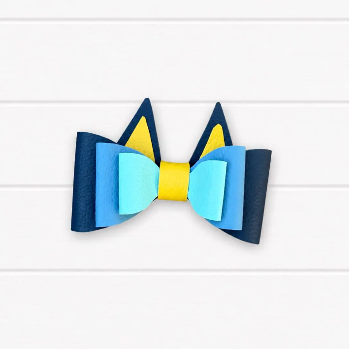Colorful bow with blue, yellow, and light blue sections on a white background. Two pointy ears coming out of the top.