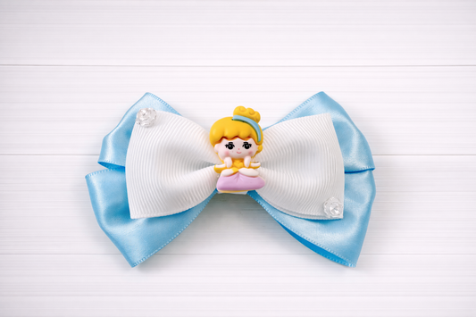 Large blue and white bow with a small Cinderella figurine on a light wooden background