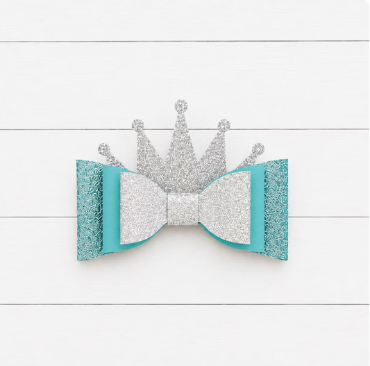 Silver crown and turquoise bow on a white wooden background