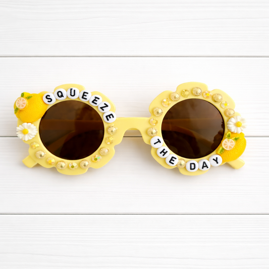 Kids flower yellow sunglasses with two lemon charms, yellow pearls and rhinestones outlining the frames, and "SQUEEZE THE DAY" text 
