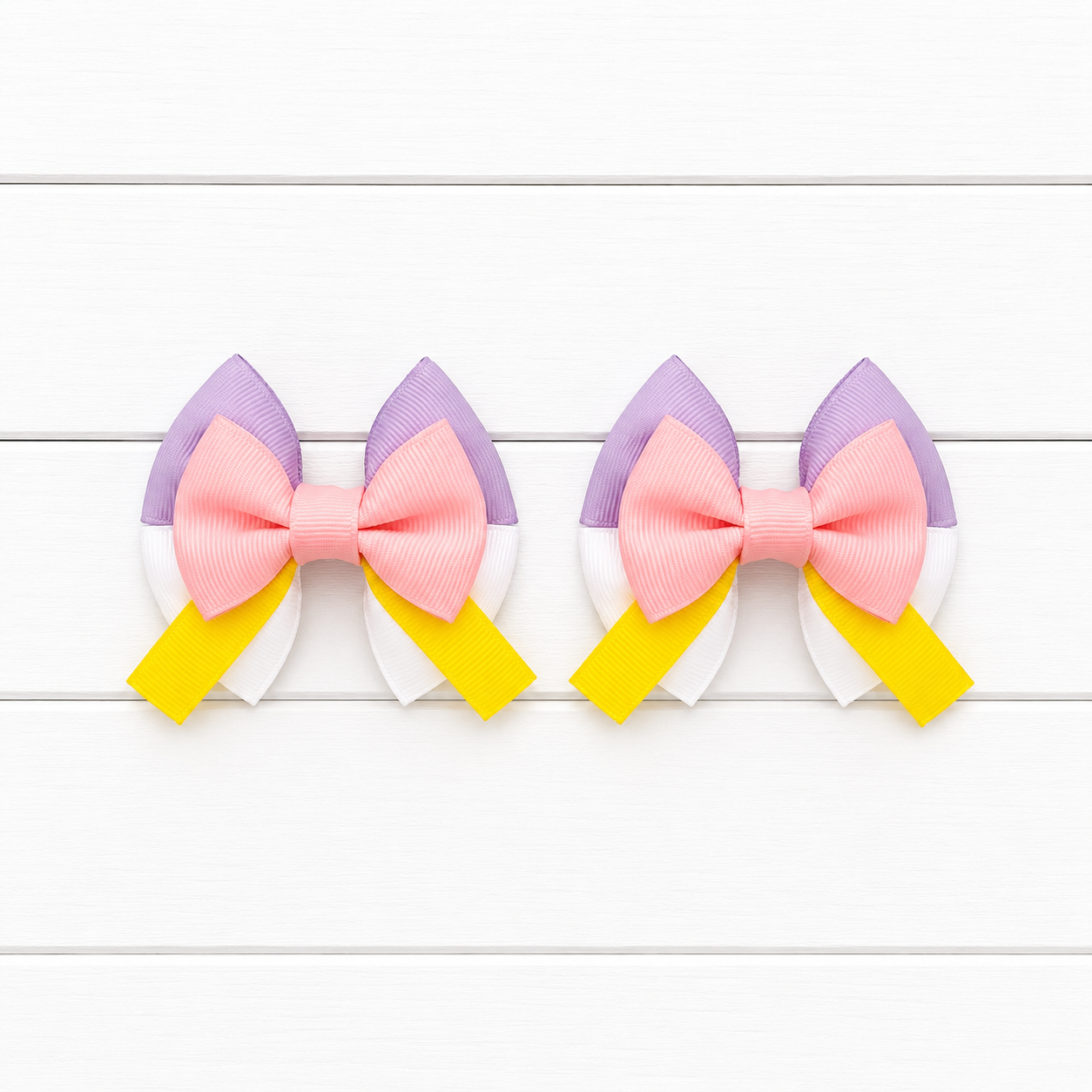 Two matching hair bows with light purple top, white bottom, light pink middle bow, and yellow tails