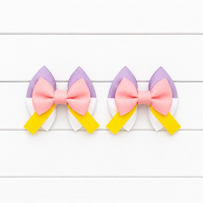 Two matching hair bows with light purple top, white bottom, light pink middle bow, and yellow tails