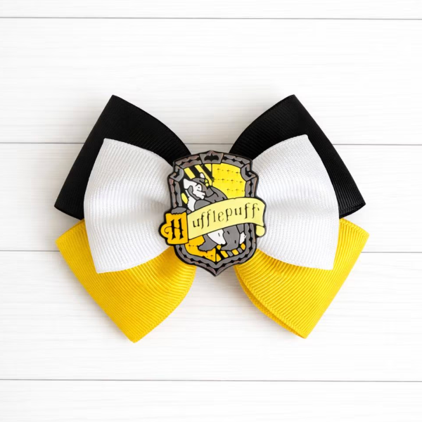Hufflepuff-themed hair bow with black, white, and yellow colors on a white wooden background