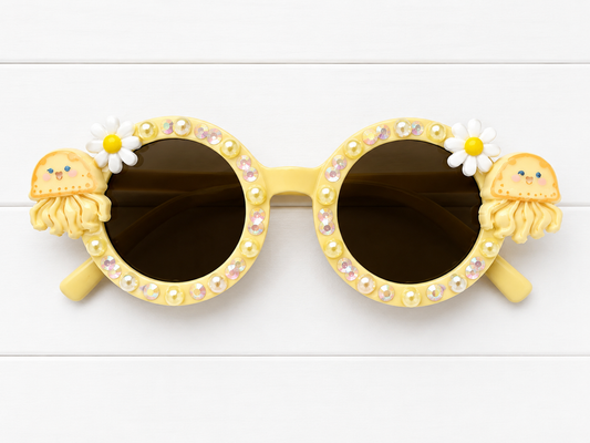 Children's round yellow sunglasses with jellyfish charms on either side, yellow pearls and rhinestones outlining the frames on a white background