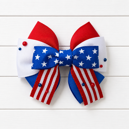Girls hair bow with red white and blue colors and stars in the middle. Featuring red and white striped ribbon at the bottom with a couple of red and blue pearl embellishments scattered throughout.