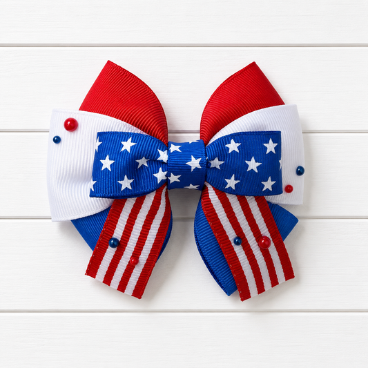 Girls hair bow with red white and blue colors and stars in the middle. Featuring red and white striped ribbon at the bottom with a couple of red and blue pearl embellishments scattered throughout.