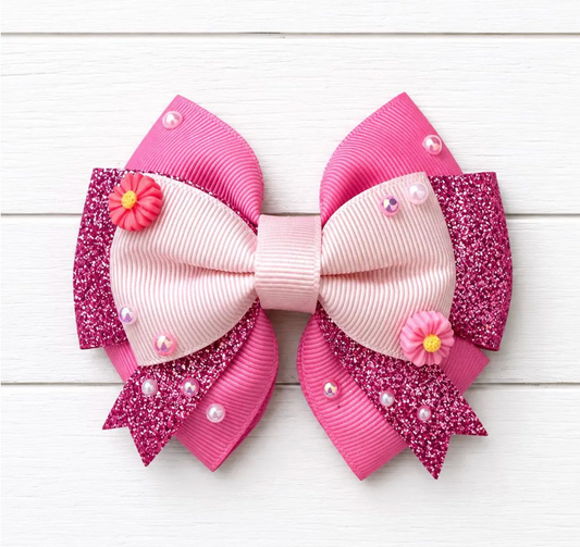 Pink and white decorative bow with flowers and beads on a light wooden background