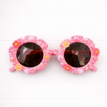 Pink kids flower sunglasses with floral embellishments on a white background