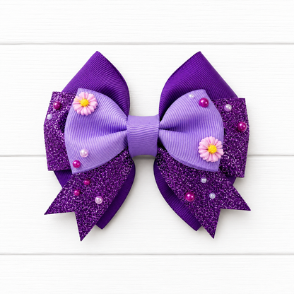 Purple glittery hair bow with purple flowers and beads on a white wooden background