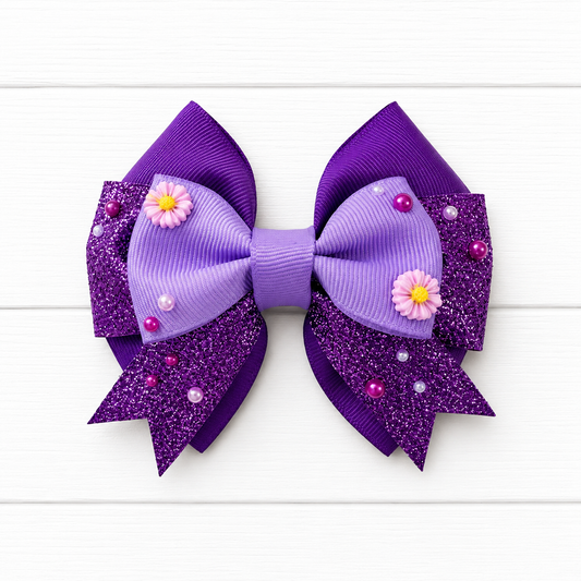Purple glittery hair bow with purple flowers and beads on a white wooden background