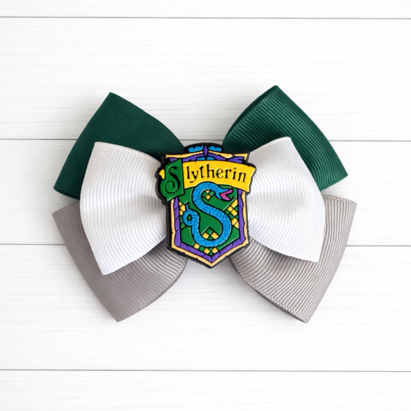 Green and grey Hair bow with Slytherin emblem on a white wooden background