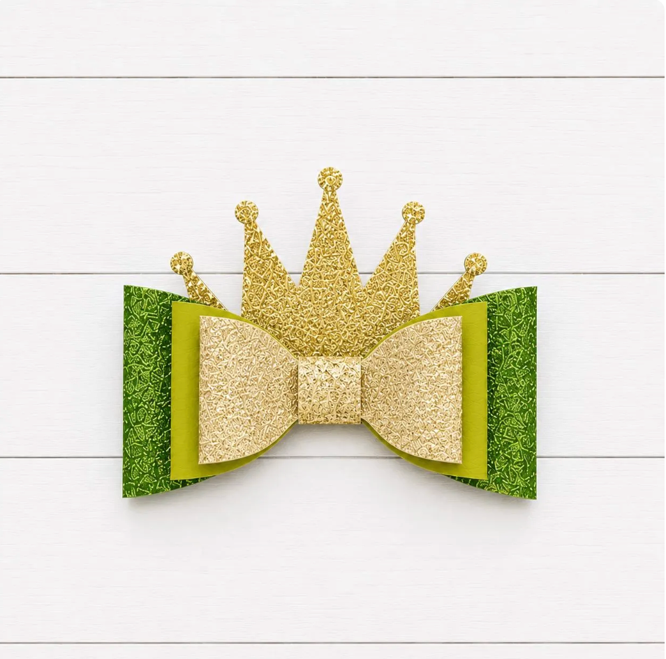 Gold glitter crown and green bow on a white wooden background