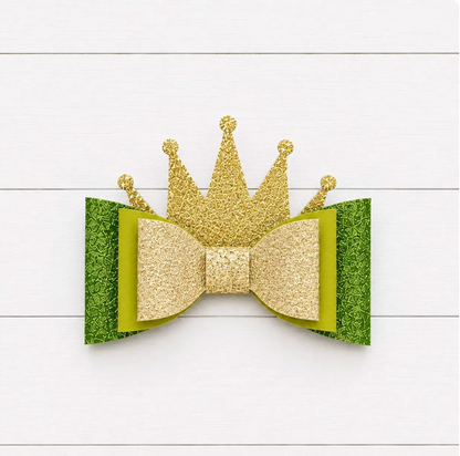 Gold glitter crown and green bow on a white wooden background