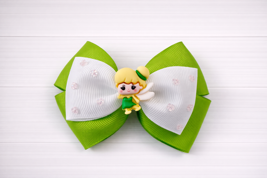 Green and white hair bow with a Tinkerbell charm in the middle on a white wooden background