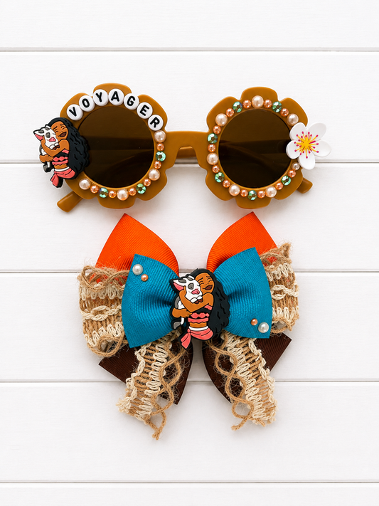 Matching bow and sunglasses. Kids brown flower sunglasses with Moana charm on left and flower on right. "VOYAGER" and orange and blue pearls and rhinestones outlines the frames. The bow has orange, brown, woven, and turquoise ribbon and features a Moana charm in the middle.