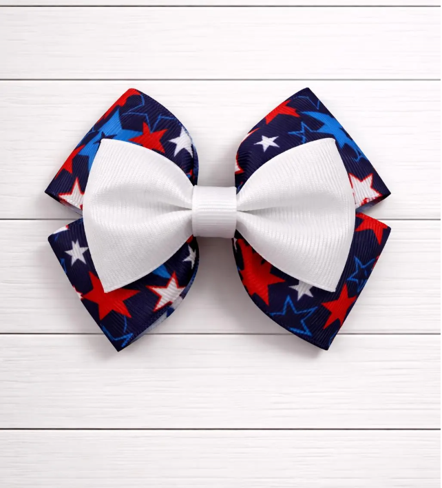 White bow with red and blue star pattern bow behind on a white wooden background