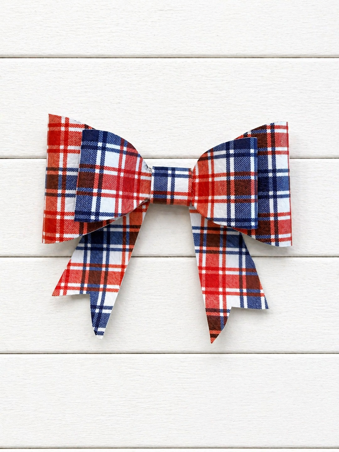 Plaid bow in red, blue, and white on a white wooden background